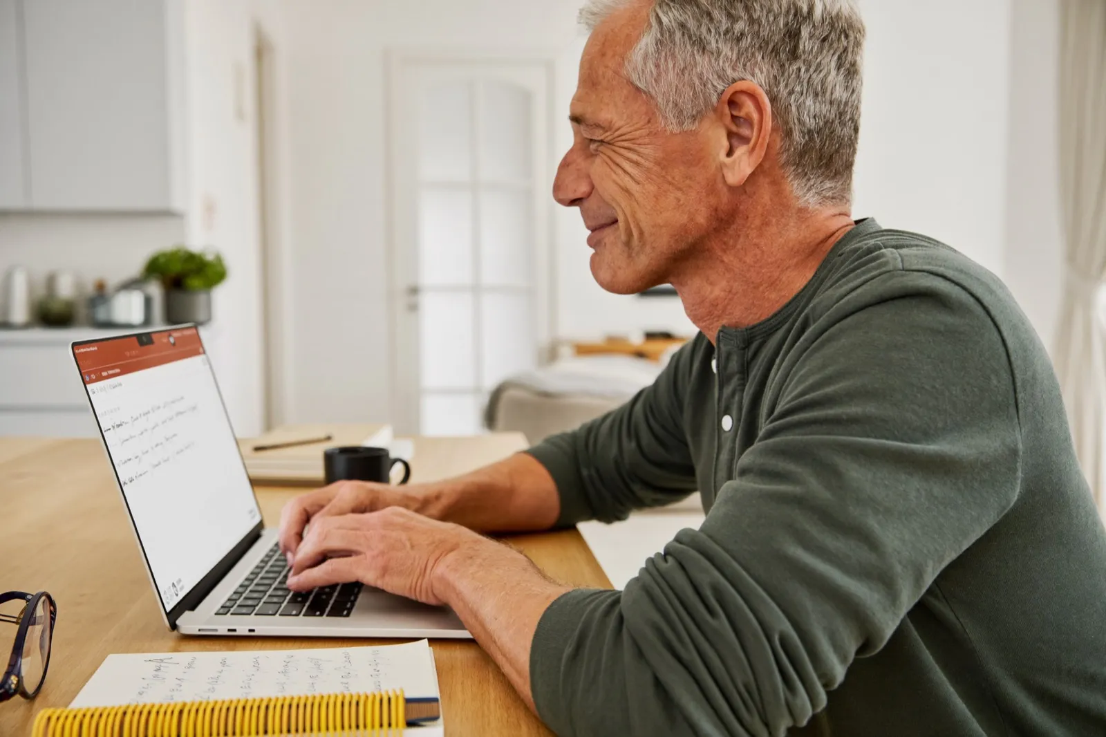 Ein Unternehmer um die 60 baut am Esstisch seine erste eigene Anwendung am Laptop